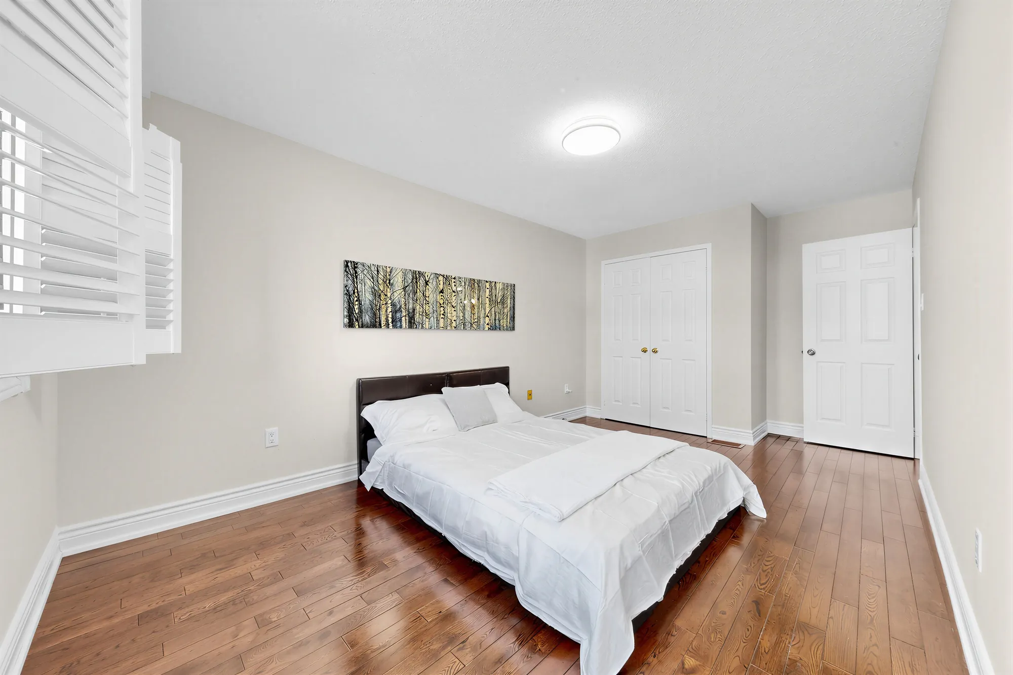 The same bedroom toward its double closet and the door