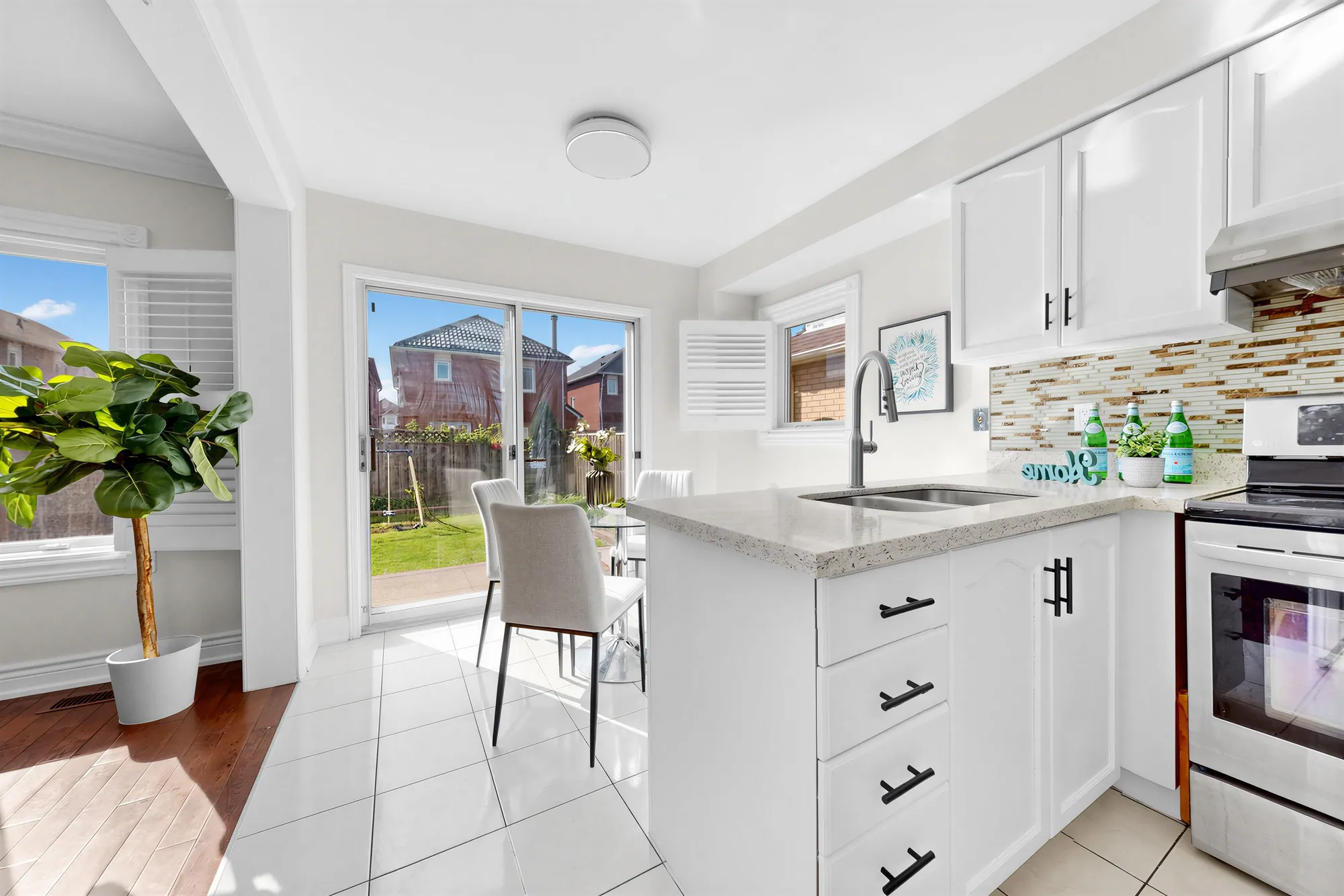 The kitchen and the breakfast area: white cabinets and quartz-look counters, a sliding glass door to the patio and the back yard