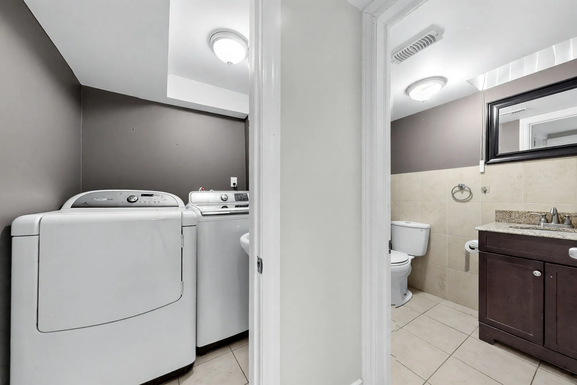 The laundry shown cleared: a washer and dryer, the bathroom through the door with its vanity and toilet