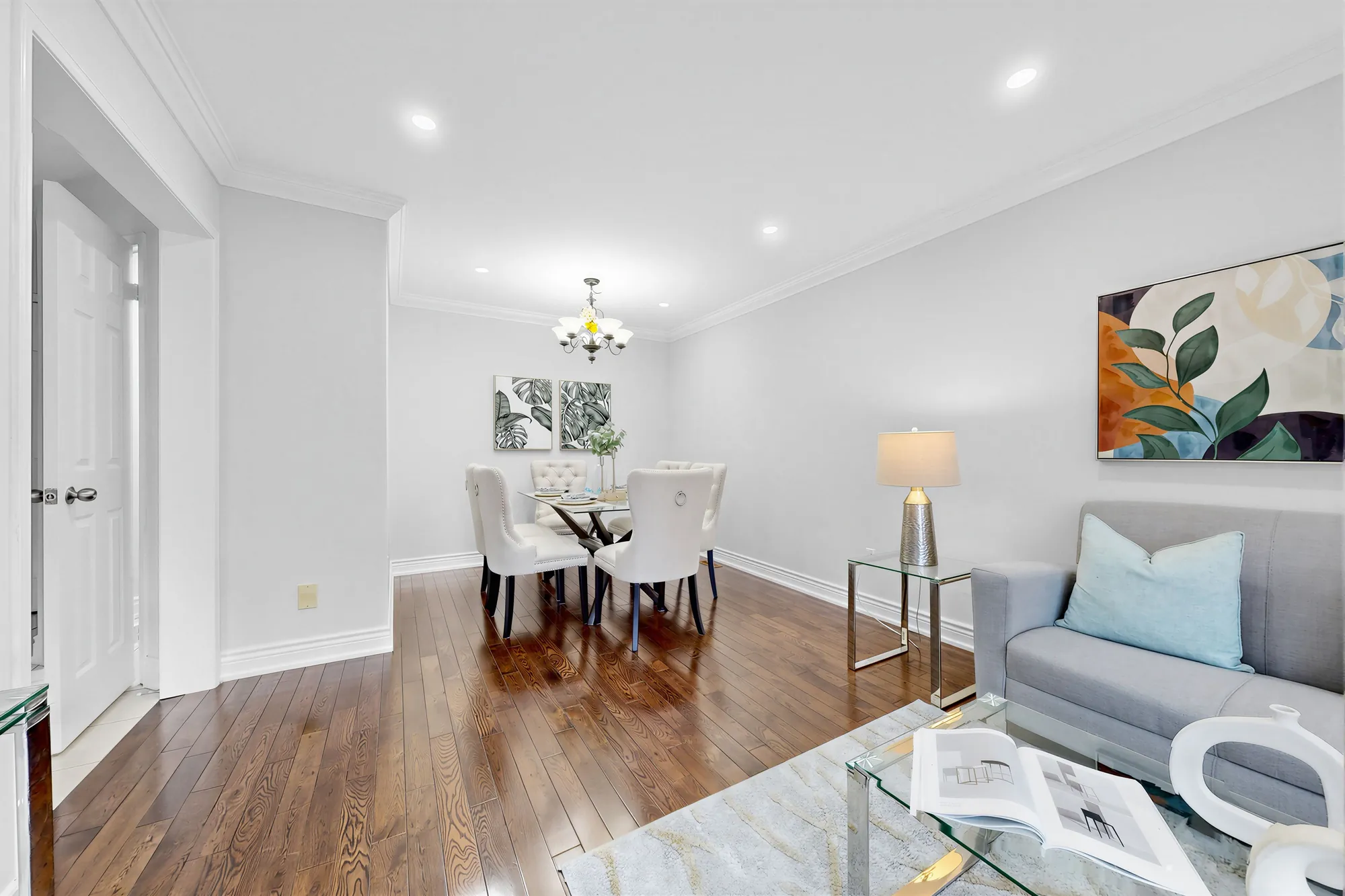 From the living room toward the dining room: the table and chairs under a chandelier, a door at the left