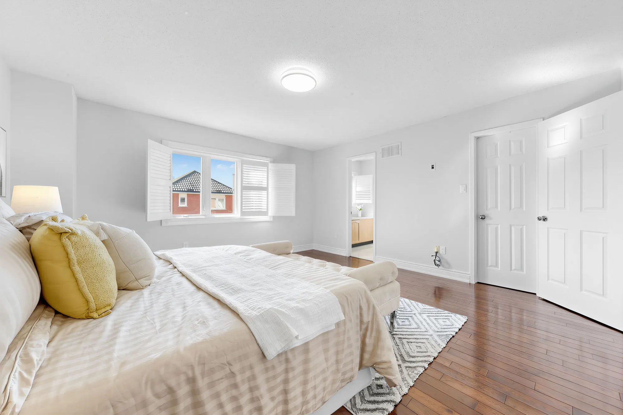The primary bedroom toward the double doors of the walk-in closet and the doorway to its bathroom