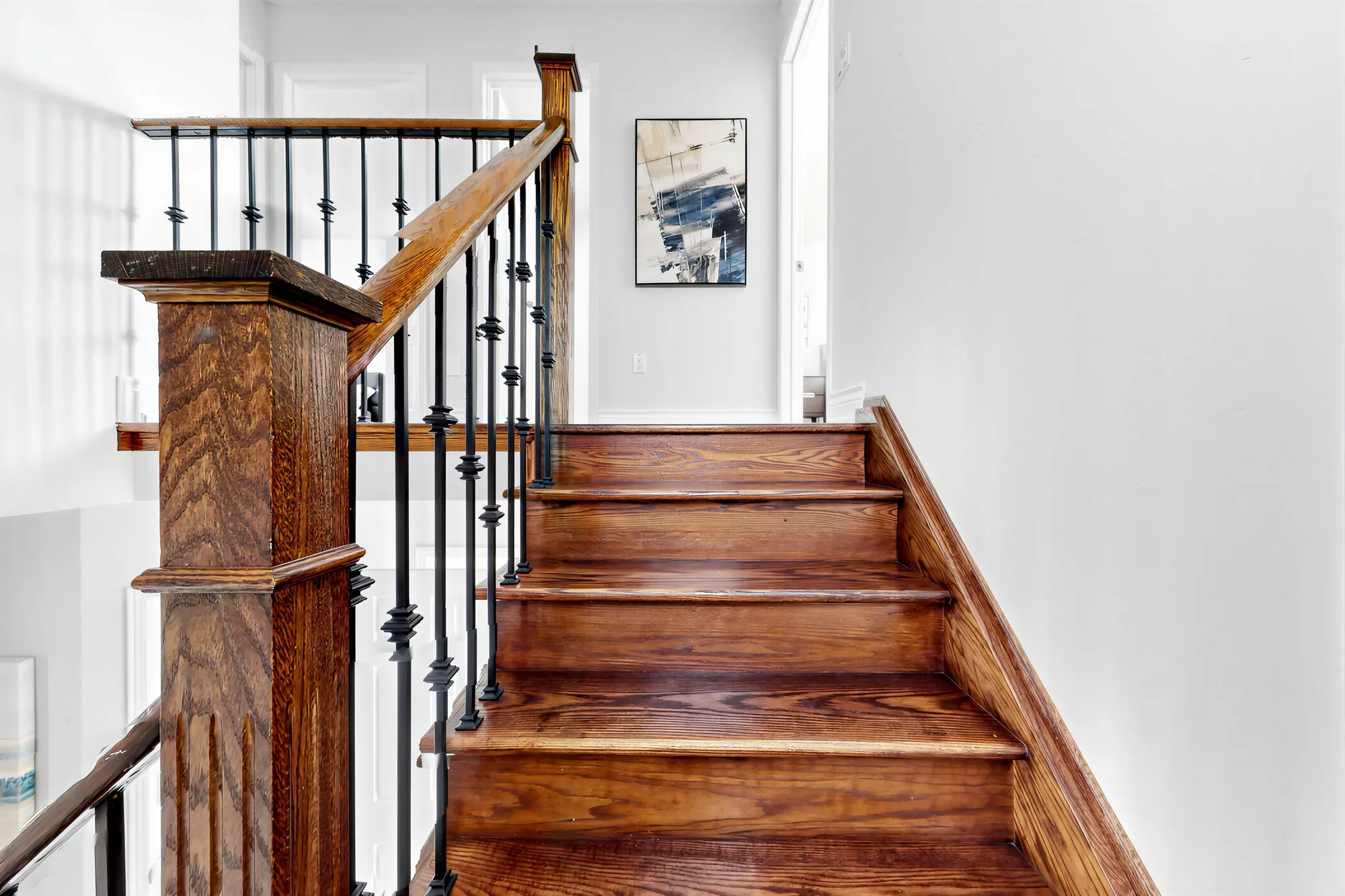 The oak stair to the upper floor with iron balusters and a square newel post